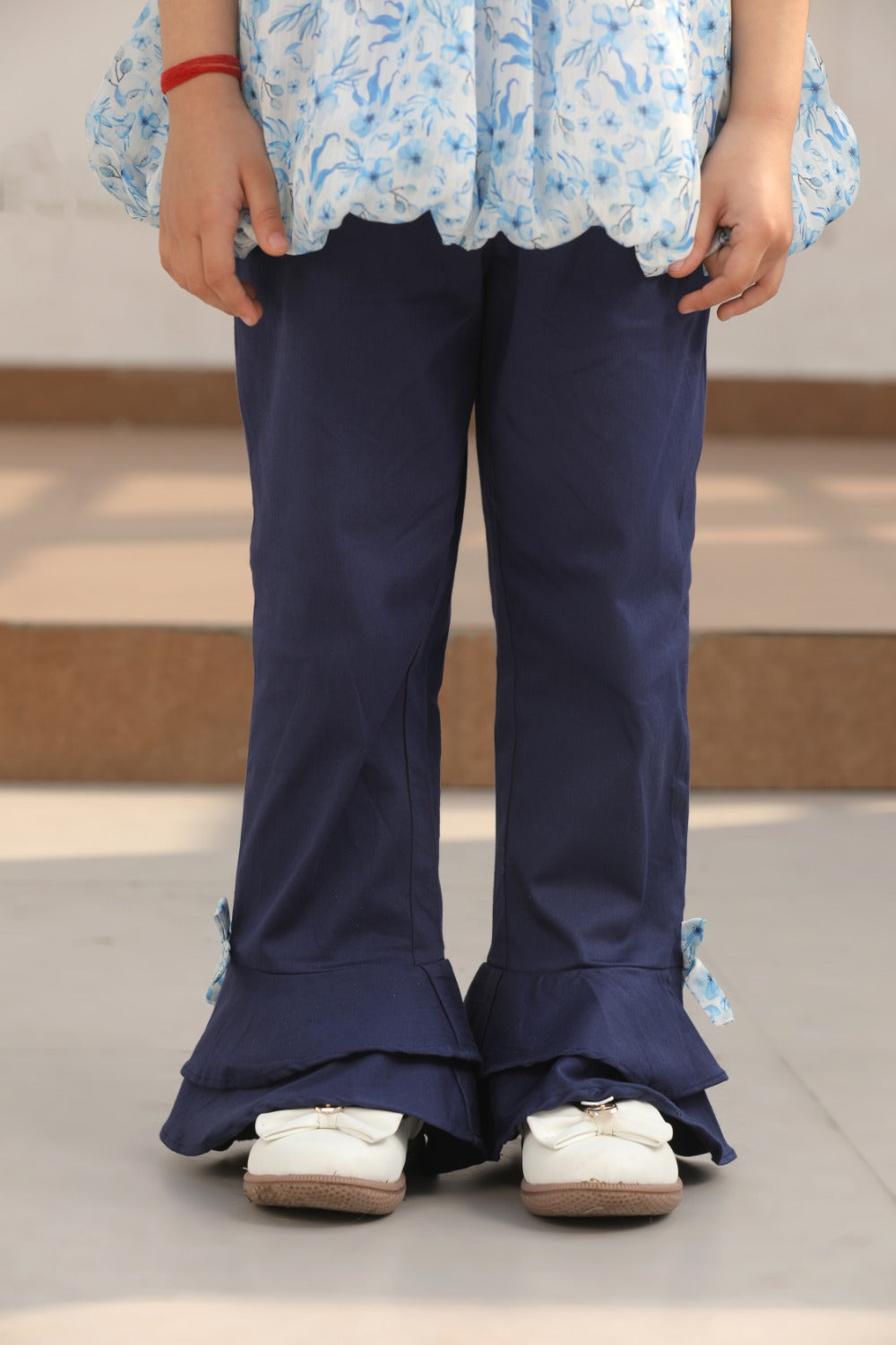 Full-length front view of girl in blue floral top and navy flared trousers