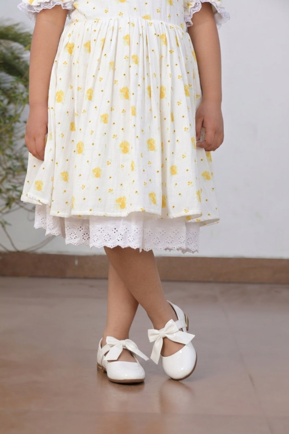 Side view of girl in cream yellow floral printed dress with lace trim