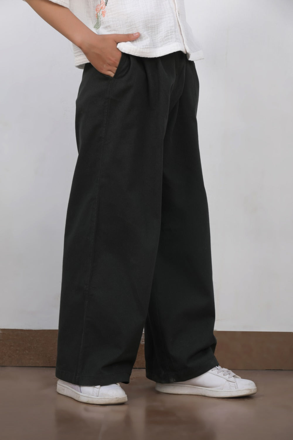 Luxe & Hardy Charles Relaxed Pants – close-up front view of black wide leg relaxed fit linen pants for boys, kids ethnic casual bottom wear, styled with white sneakers, indoor setting