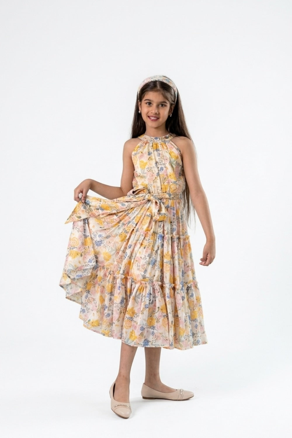 Girl in yellow and white floral halter dress holding out skirt, full-length front view
