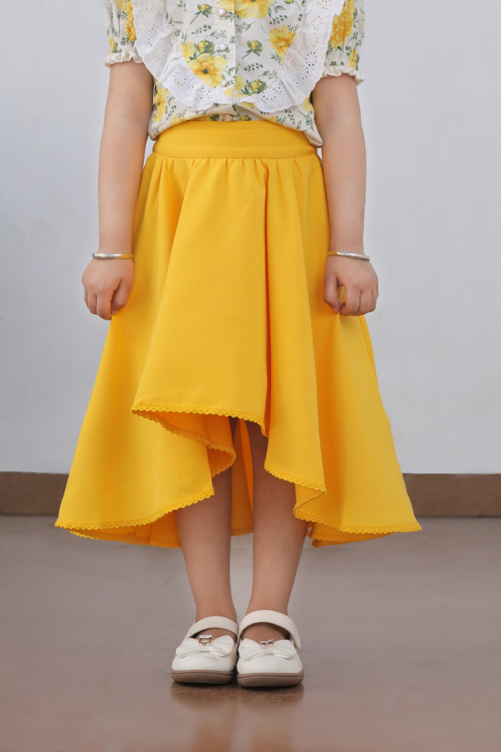 Side view of girl in white floral puff-sleeve top and yellow flared skirt