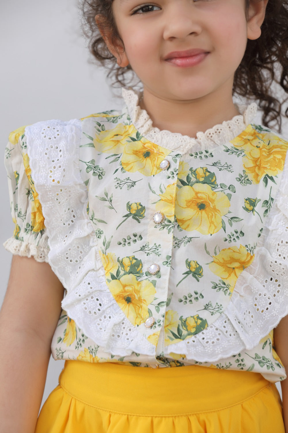 Close-up of girl smiling in white floral top and yellow skirt