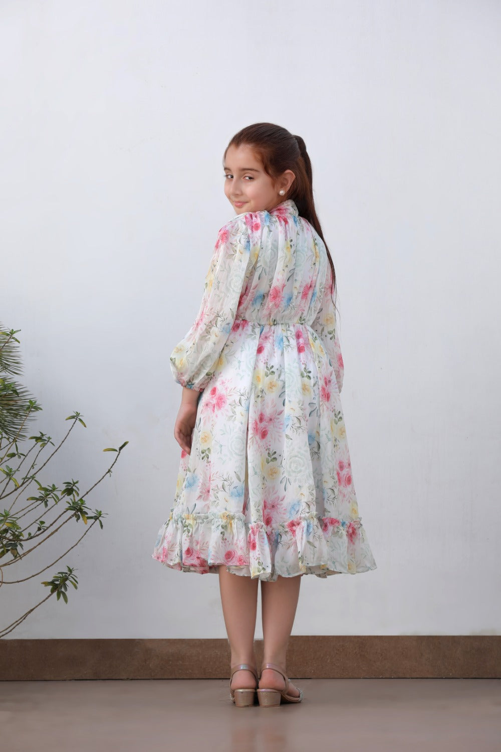 Full-length side view of girl in white floral long-sleeve midi dress