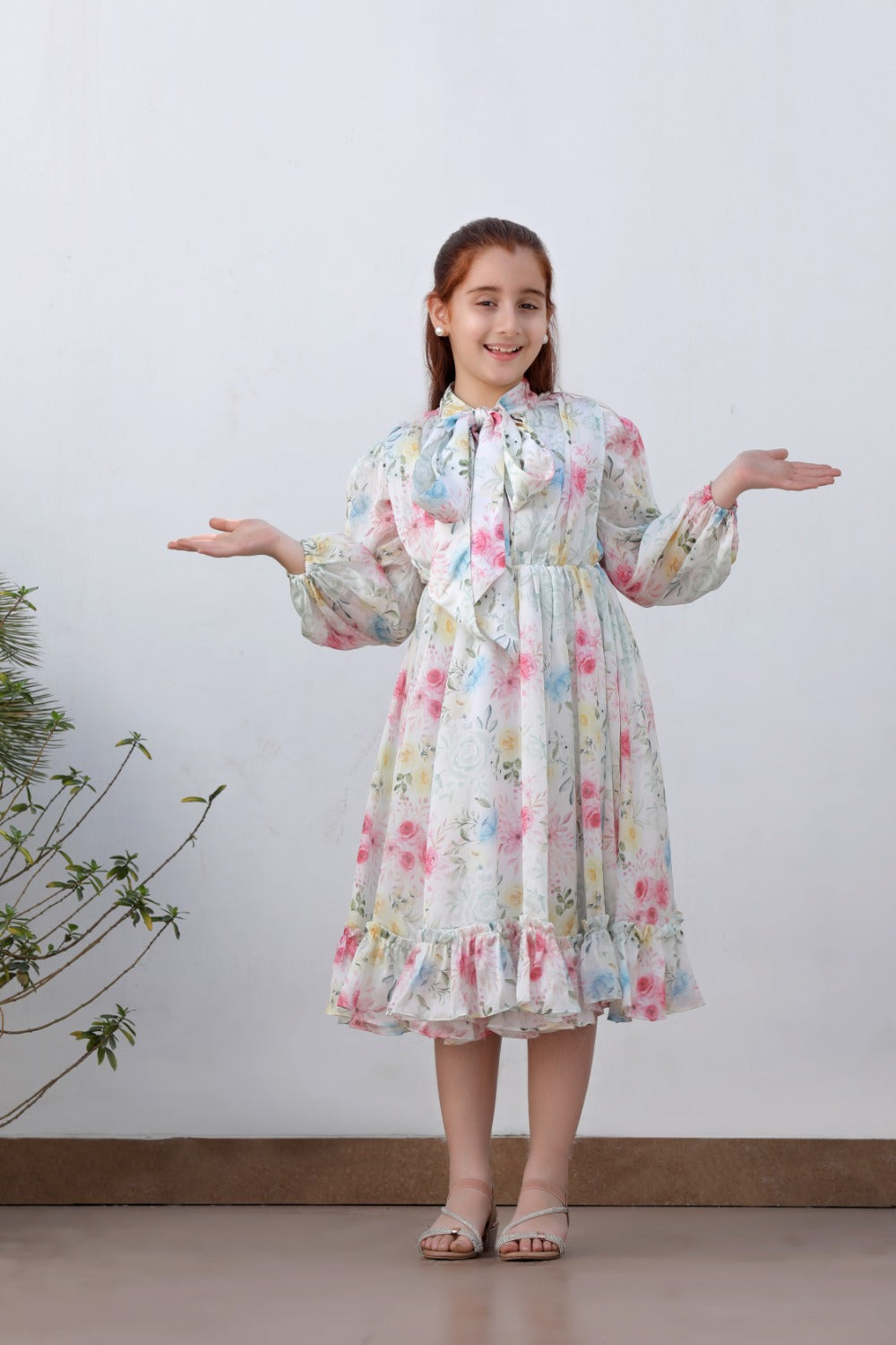 Girl in white floral long-sleeve midi dress with bow neckline, full-length front view