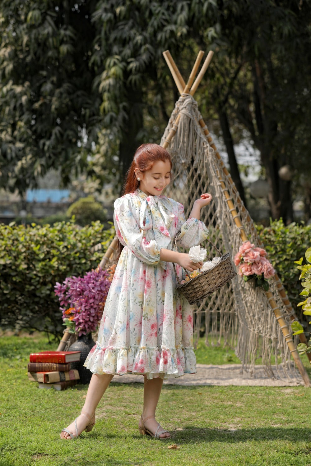 Girl in white floral dress posing outdoors near a decorative teepee"