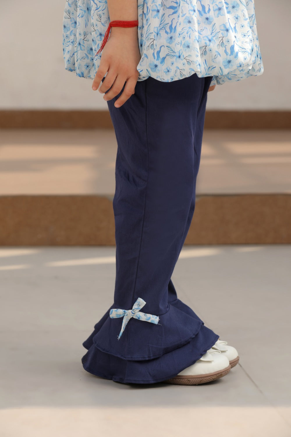 Back view of girl in blue floral tie-shoulder top and navy flared pants