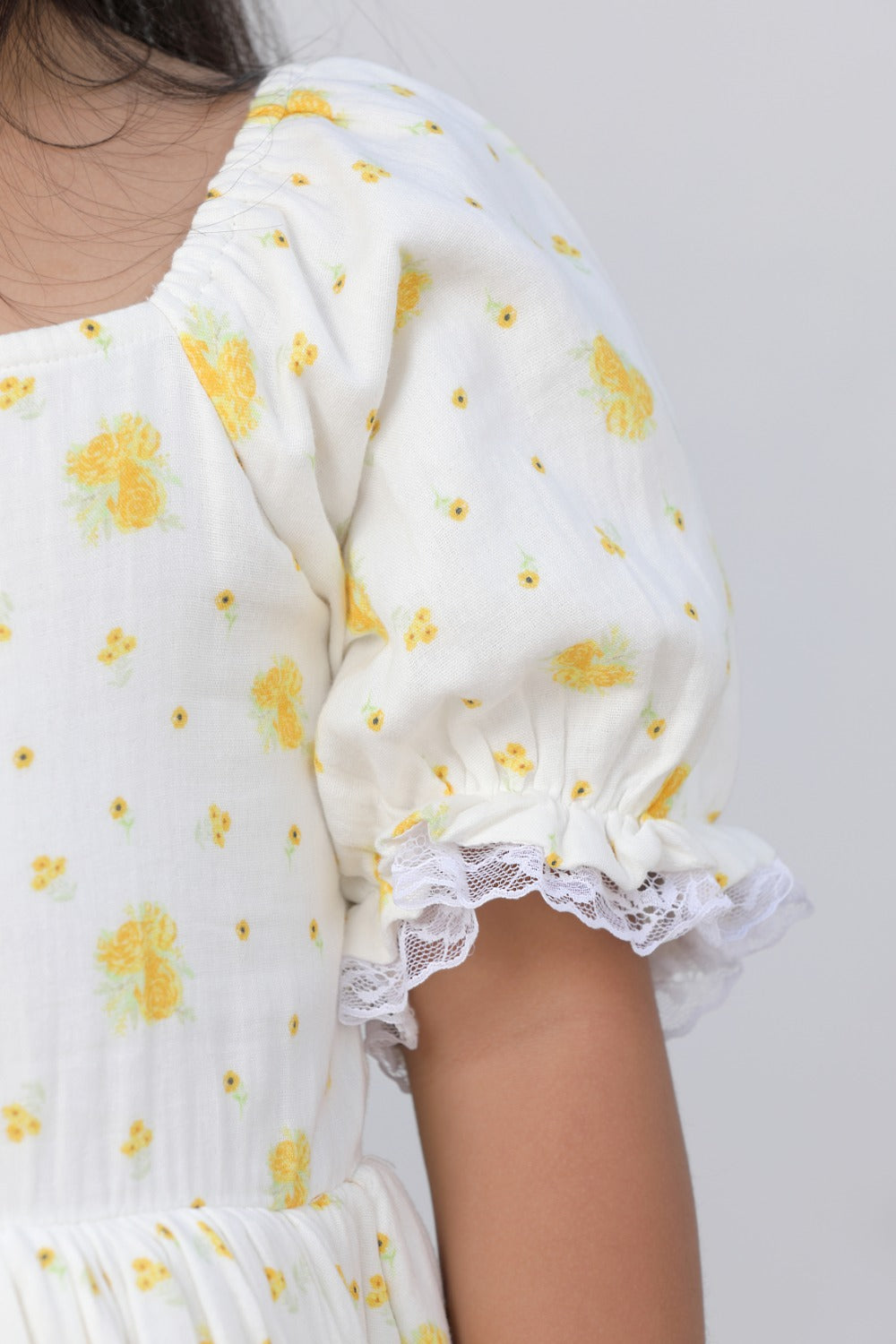 Close-up of puff sleeve with lace trim detail on cream floral dress
