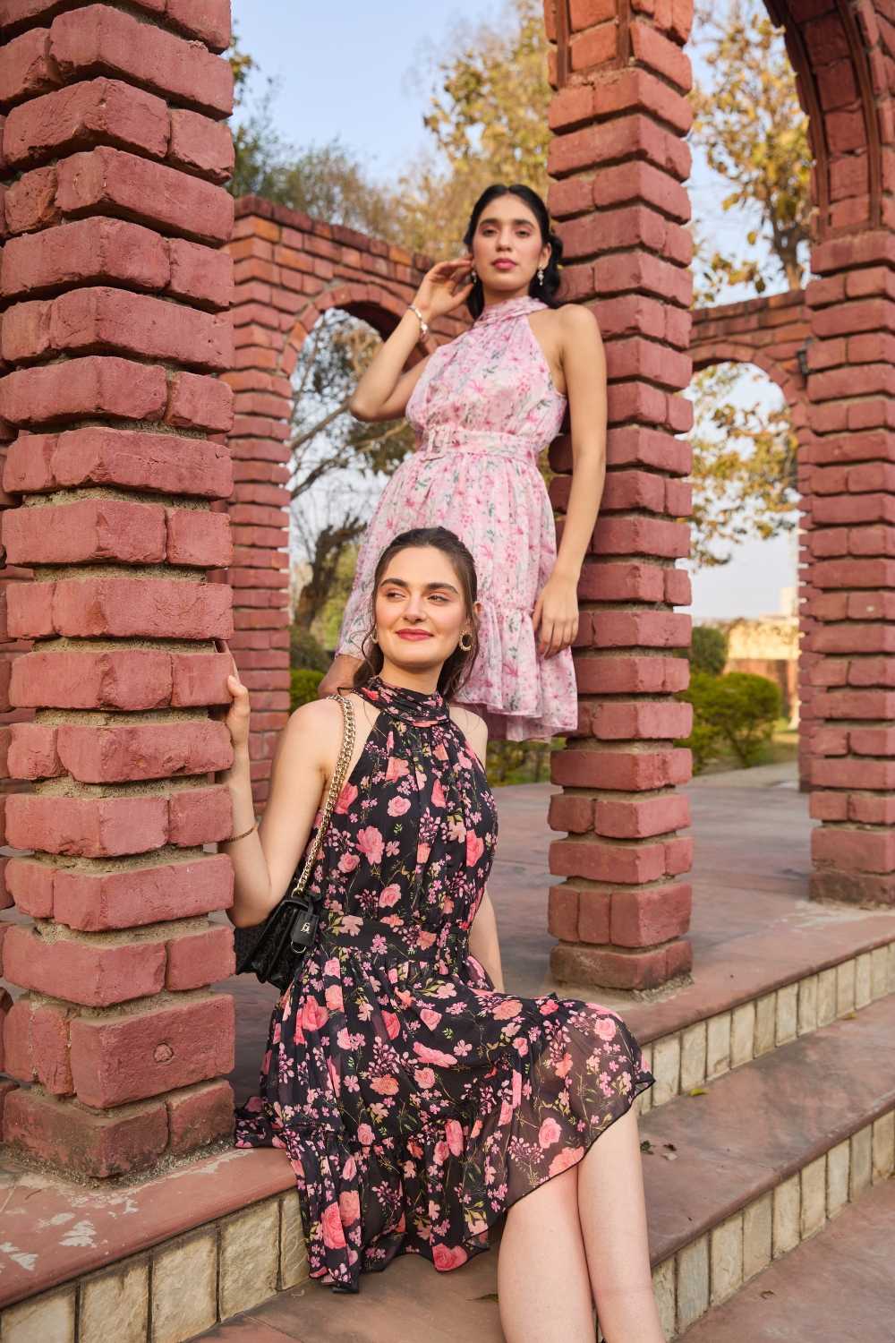 Luxe & Hardy Iris Halter Dress in Lavender – full length outdoor shot against brick wall, showcasing lavender floral halter neck tiered mini dress with ruffle layers