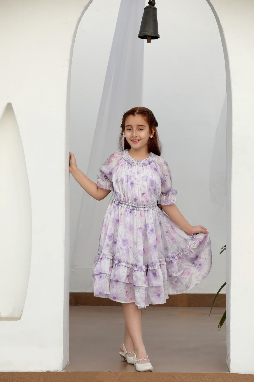 Full-length front view of girl in lilac floral dress with smocked waist outdoors