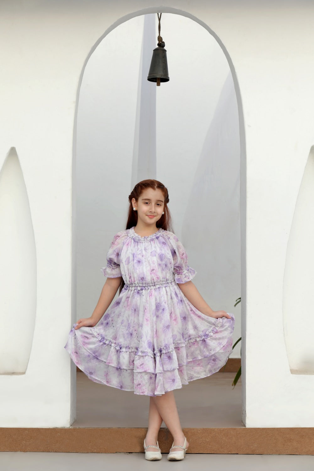 Girl in lavender watercolour floral puff-sleeve midi dress posing in an arched doorway