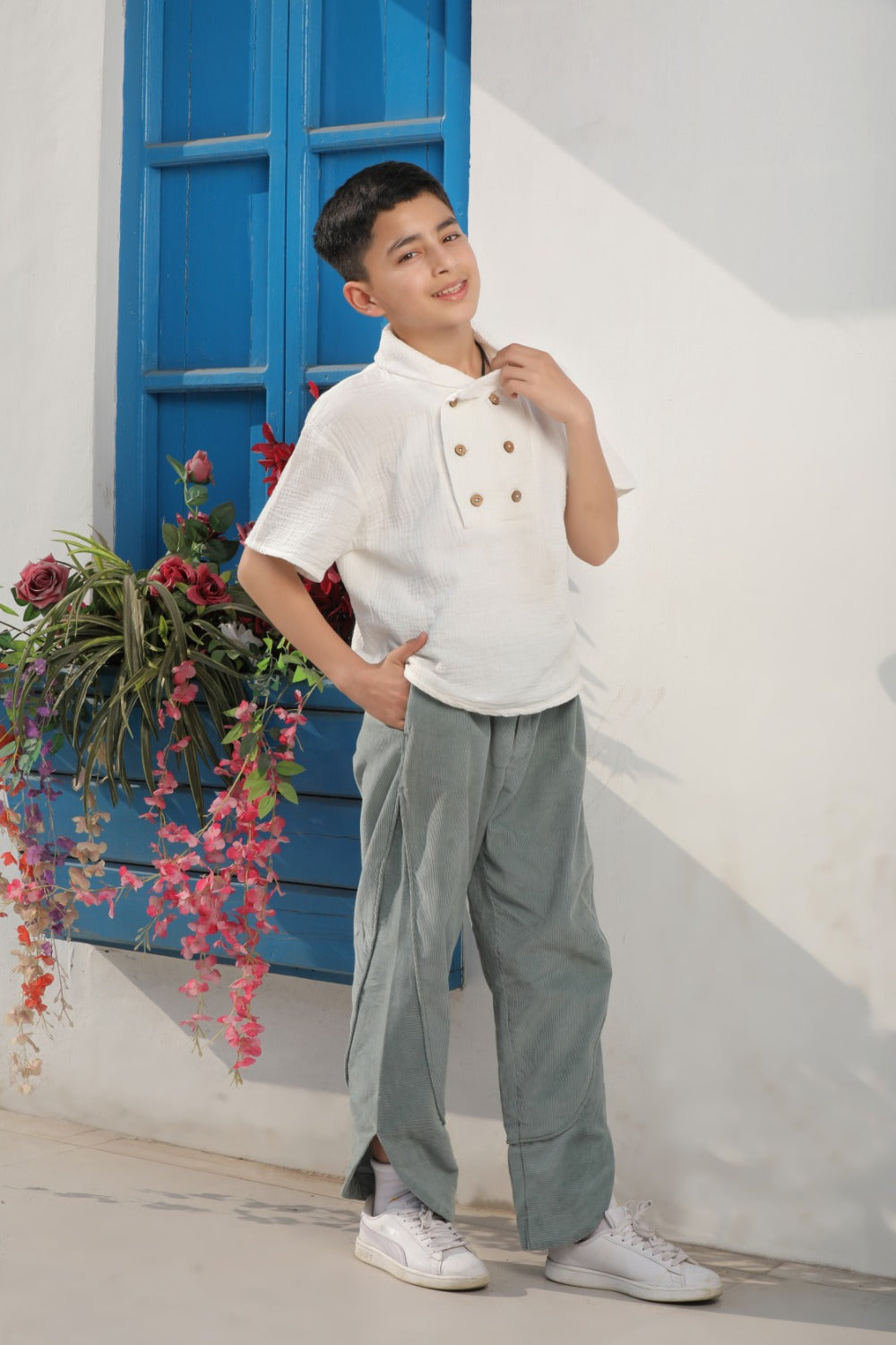 Luxe & Hardy Milo Textured Tee – full length front view of white textured linen short sleeve double button boys shirt with sage green wide leg pants, kids ethnic casual party wear shirt, blue door outdoor setting