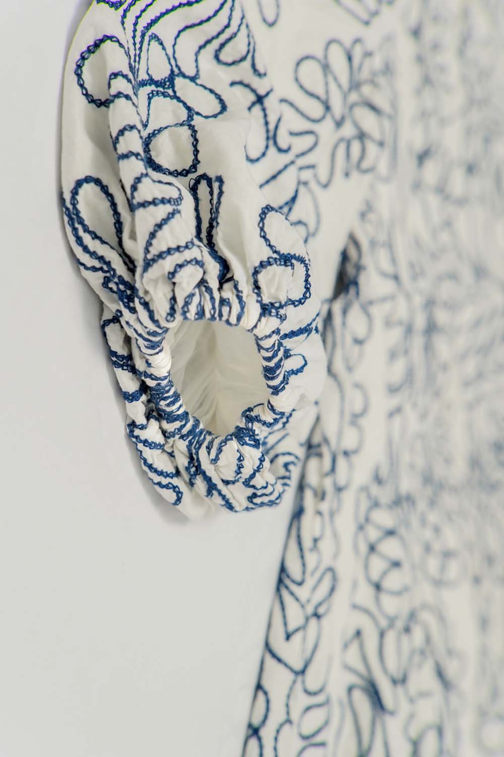 Close-up of white balloon sleeve with blue floral print and ruffle cuff detail